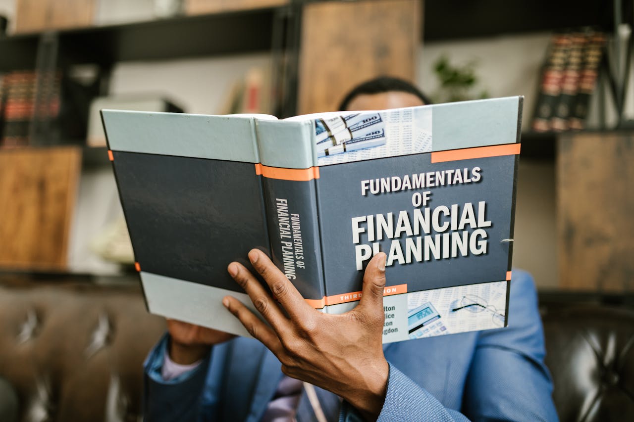 services-03 A professional individual in a suit reading 'Fundamentals of Financial Planning' indoors.